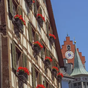 Medieval half-timbered house with lush flowers under clock tower