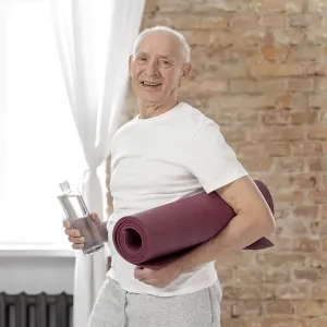 Medium shot senior man holding yoga mat Medium shot senior man holding yoga mat