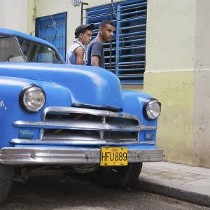 Two men standing behind a classic car