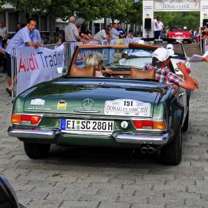 Mercedes Benz 280 SL, green Mercedes classic car at an outdoor event with people wearing summer clothes