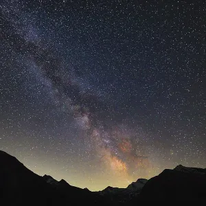 The Milky Way illuminates the night sky over the mountains