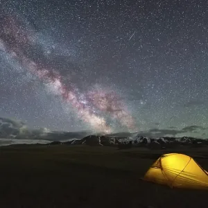 Milky Way on Starry Night Sky with Airglow and Yellow Glowing Tent Milky Way on Starry Night Sky with Airglow and Yellow Glowing Tent