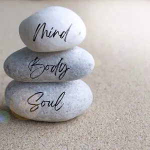 Mind, body and soul text on zen stones with bright shining light