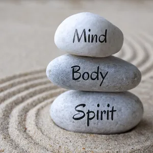 Mind, body and soul text on zen stones with sand background