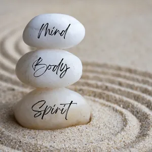 Mind, body and soul text on zen stones with sand background