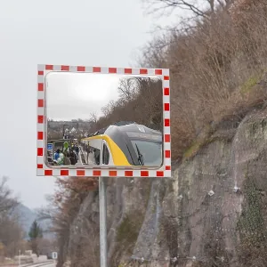 A mirror depicts a train and people waiting in a landscape