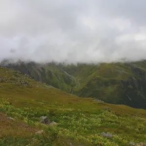Misty mountain landscape with green meadows and a narrow path