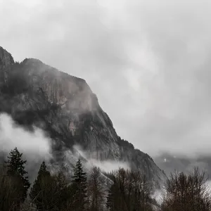 Misty mountains with fog rolling over forested slopes under cloudy skies along the lower mainland coast in British Misty mountains with fog rolling over forested slopes under cloudy skies along the lower mainland coast in British