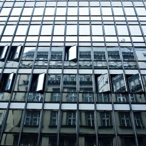A modern building with a glass facade reflecting older architecture