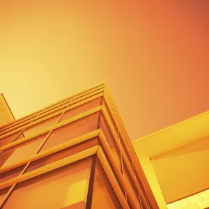 A modern building with glass surfaces under an orange sky