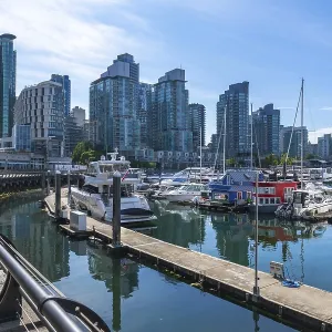 Modern buildings rise above a marina filled with yachts and houseboats