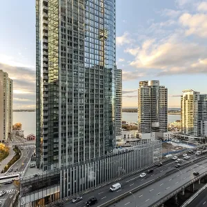 A modern city view featuring skyscrapers and a busy road under a colorful sunset in Toronto