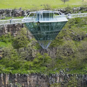 Modern glass bridge crosses green gorge with trees and rocks Modern glass bridge crosses green gorge with trees and rocks