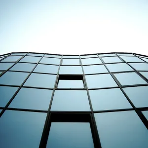 Modern glass building with blue sky reflection creating a geometric urban aesthetic