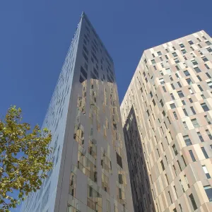 Two modern high-rise buildings with glass facades under a clear blue sky