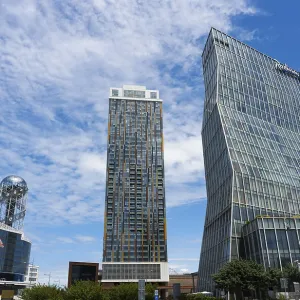 Two modern high-rise buildings with glass facades under cloudy sky