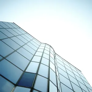 Modern skyscraper with glass windows reflecting a gradient blue sky in a sleek vertical design