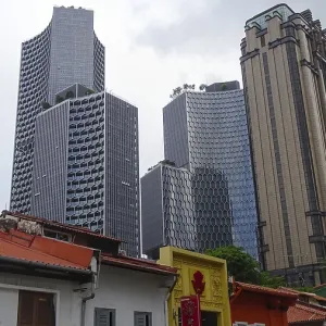 Modern skyscrapers tower over the rooftops of a city under a slightly cloudy sky Modern skyscrapers tower over the rooftops of a city under a slightly cloudy sky