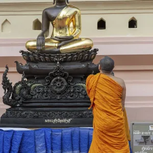 Monk in front of a Buddha statue