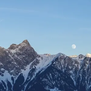 full moon rising into the evening sky over a winter mountain landscape in the Swiss Alps full moon rising into the evening sky over a winter mountain landscape in the Swiss Alps