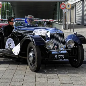 Morgan 4-4-2 Seater, black vintage convertible with two drivers on a paved road during a race