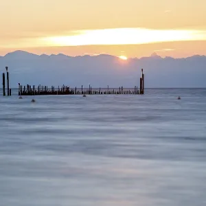 Morning waves under a warm sky with mountain silhouettes