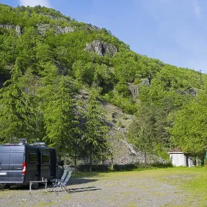 Motorhome is parked on an area in a mountainous and wooded area