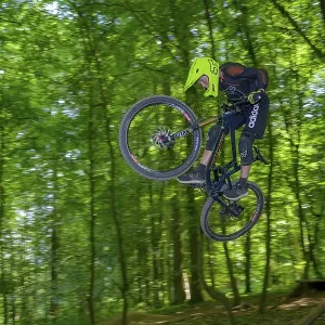 Mountain biker, downhill biker jumps over a ramp on a downhill trail