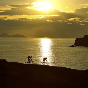 Two mountain bikers cycling on a rocky coast