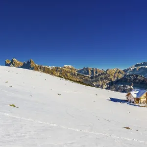 Mountain chalet at high altitude in front of snow-capped peaks of the Dolomites