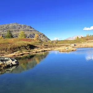Mountain lake reflects landscape under clear sky with autumn colors