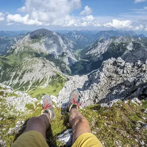 Mountain landscape, hiker lets his legs dangle Mountain landscape, hiker lets his legs dangle