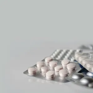 A mountain of packaged pills reflected in white glass