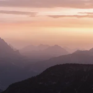 Les silhouettes de montagnes pendant un coucher de soleil rose et orange.