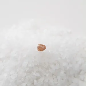 Mountain of white salt with one grain of pink salt
