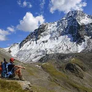 Mountaineer with backpack on stone and Sellrain mountains in the background Mountaineer with backpack on stone and Sellrain mountains in the background