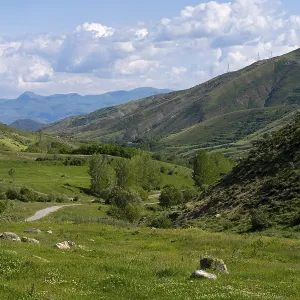 Mountainous valley with green meadow under a blue sky with clouds and power lines Mountainous valley with green meadow under a blue sky with clouds and power lines