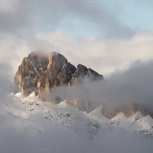 Mountains shrouded in light clouds under a sky flooded with light at the Passo di Falzarego