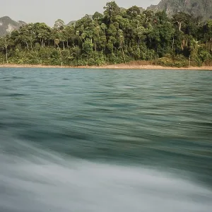 Moving water in front of a picturesque coastline with forest in the background