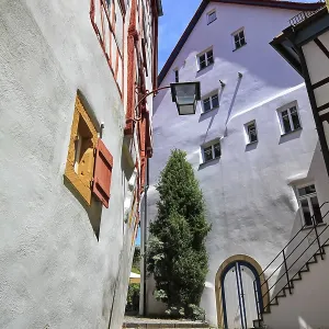 Rue étroite avec des maisons à colombages et une lanterne nostalgique sous un ciel bleu à Bad Wimpfen.