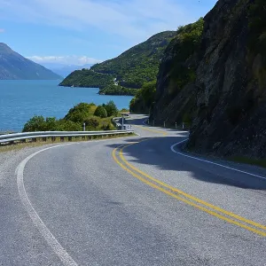 Narrow, winding road meanders along a lake through mountain landscape