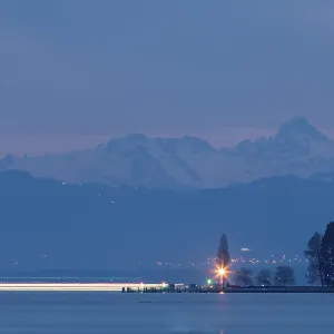 Night over a lake, with rays of light and mountains in the background Night over a lake, with rays of light and mountains in the background