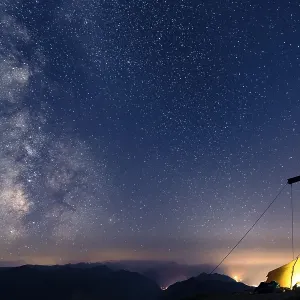 Night sky with stars and milky way over Lechtal mountains, in the foreground summit cross of the Geierkopf with tent, Reutte, Ammergau Alps, Tyrol, Austria, Europe Night sky with stars and milky way over Lechtal mountains, in the foreground summit cross of the Geierkopf with tent, Reutte, Ammergau Alps, Tyrol, Austria, Europe