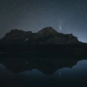 Night sky with stars over a mountain and its reflection in a calm lake Night sky with stars over a mountain and its reflection in a calm lake