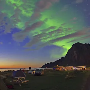 Northern lights (aurora borealis) and evening glow over tents and cars Northern lights (aurora borealis) and evening glow over tents and cars