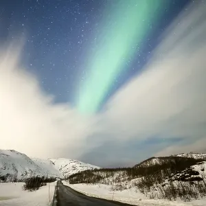 Northern lights over road with snow mountains Northern lights over road with snow mountains