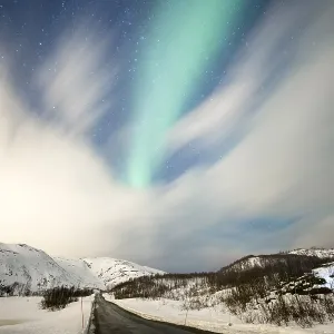 Northern lights over road with snow mountains Northern lights over road with snow mountains