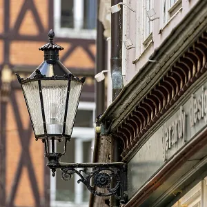 Nostalgic lantern next to a building in front of half-timbered buildings and windows in urban space Nostalgic lantern next to a building in front of half-timbered buildings and windows in urban space