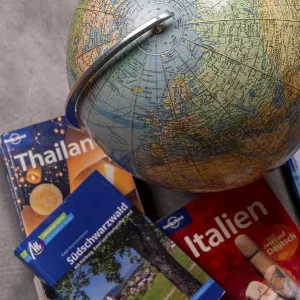 An old-fashioned globe next to travel guides for Thailand
