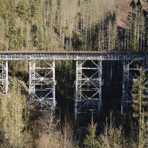 Old metal railway bridge surrounded by a thick forest in sunlight Old metal railway bridge surrounded by a thick forest in sunlight